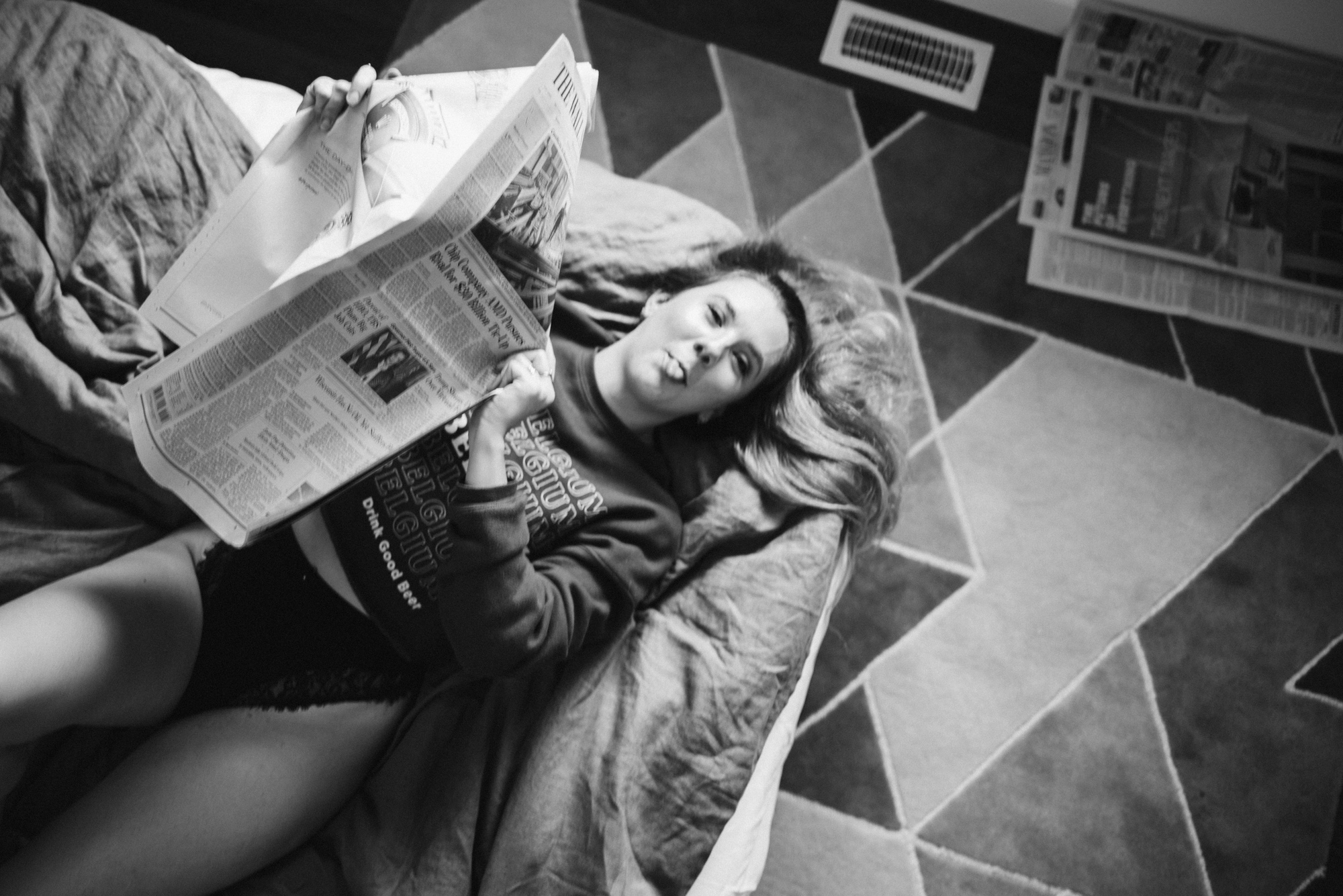 Clair Tillotson laying on the floor reading a newspaper